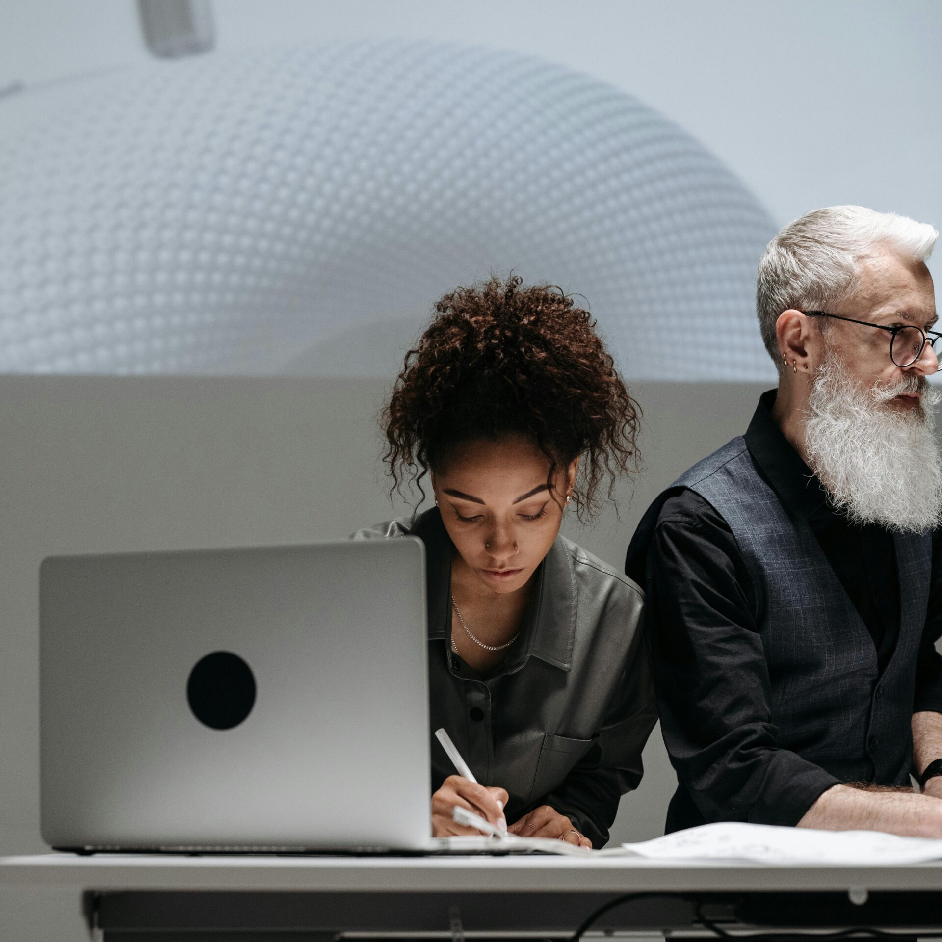 Two designers collaborating on a project with a futuristic model projection, illustrating teamwork and innovation.